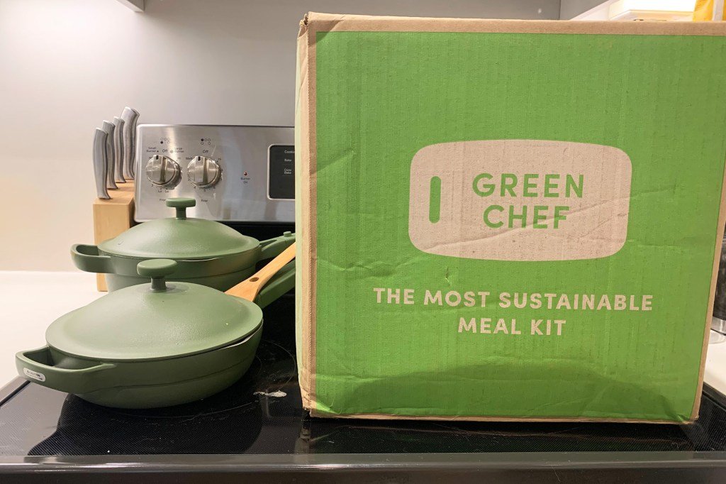 A green cook box and two green pots and pans on a stove